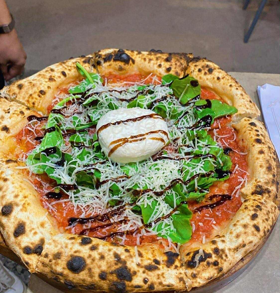 Wood-fired signature pizza with fresh basil